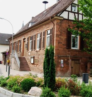 Heimatmuseum an der alten Dorfstraße mit einem Blumenbeet im Vordergrund